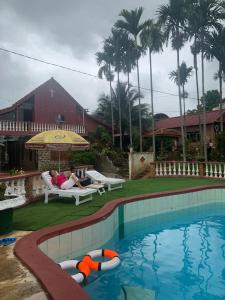 a pool with two people sitting under an umbrella at Gia lai Homestay Phương My in Pleiku
