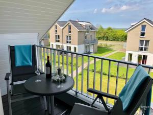 - une table avec deux verres de vin sur le balcon dans l'établissement Familienhaus an der Nordsee - Sauna - Kamin - Südterrasse direkt über dem Wasser, à Wangerland