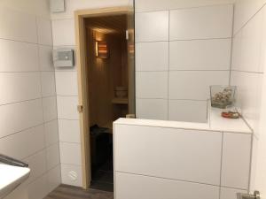 ein Badezimmer mit weißen Fliesenwänden und einem Spiegel in der Unterkunft Familienhaus an der Nordsee - Sauna - Kamin - Südterrasse direkt über dem Wasser in Wangerland