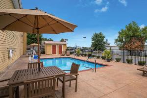 a patio with a table and an umbrella next to a pool at Best Western Conway in Conway
