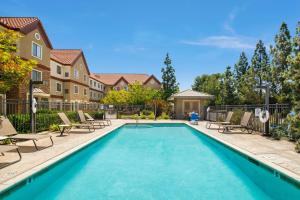 Sonesta ES Suites San Diego - Rancho Bernardo في رانشو برناردو: مسبح مع كراسي وكراسي بجوار منزل