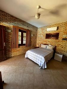 a bedroom with a bed and a brick wall at Pousada Solar das Fontes in Beberibe