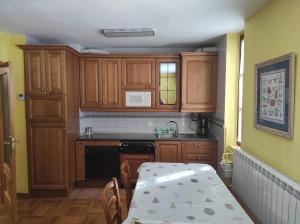 uma cozinha com armários de madeira, uma mesa e um lavatório em Apartamento Parque Europa em Ezcaray