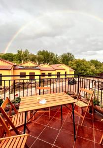 un patio con una mesa de madera, sillas y un arco iris en Alojamiento Rural Los Hacheros, en Tragacete