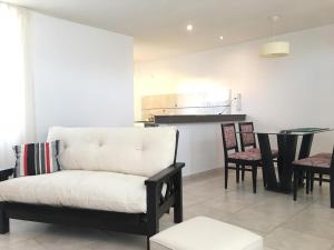 Una sala de estar con un sofá blanco y sillas. en COMPLEJO LAVANDAS, en Balneario El Condor