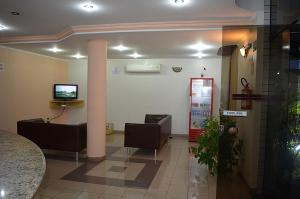 uma sala de espera com cadeiras e uma televisão num quarto em SG Palace Hotel em Taubaté