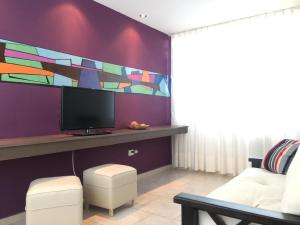 - un salon avec une télévision et un mur violet dans l'établissement COMPLEJO LAVANDAS, à Balneario El Cóndor