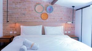 1 dormitorio con cama blanca y pared de ladrillo en Masaya Bogotá en Bogotá