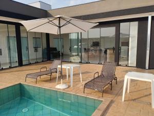 eine Terrasse mit einem Tisch, Stühlen und einem Sonnenschirm in der Unterkunft Casa de temporada em olimpia sp thermas laranjais in Olímpia