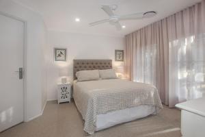 a white bedroom with a bed and a ceiling fan at Vitamin Sea Pet Friendly in Hawks Nest