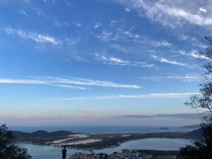 una persona parada en la cima de una colina con vistas a un lago en Casa do Mirante quarto 301 en Florianópolis