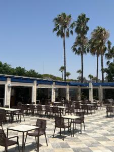 un patio con mesas, sillas y palmeras en Velero en el corazón de El Puerto, en El Puerto de Santa María