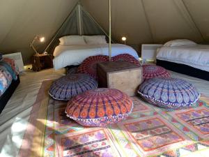 a tent with four pillows on a rug in a room at Luxury 6 metre Bell Tent & Outdoor Bathroom, WIFI, TV and firepit, in Coodanup