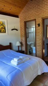 duże łóżko w sypialni z ceglaną ścianą w obiekcie Caminho do Sol w mieście Monte Verde