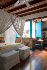 um quarto com uma cama com cortinas e um sofá em Casa Turquesa - Maison D´Hôtes em Paraty