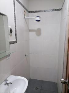Baño blanco con lavabo y espejo en Hostal Pacífico Huánuco en Huánuco