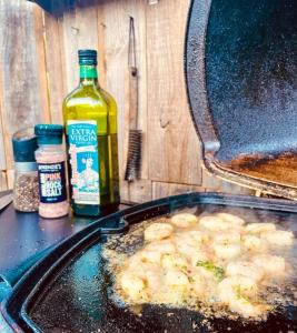 a table with a pan of food and a bottle of alcohol at Luxury 6 metre Bell Tent & Outdoor Bathroom, WIFI, TV and firepit, in Coodanup +4 photos