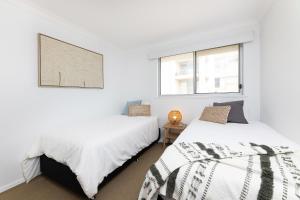 Cet hébergement comprend 2 lits dans une chambre dotée de murs blancs et de fenêtres. dans l'établissement El Sandi, Unit 10, 14-18 North Street, à Forster