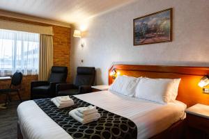 ein Hotelzimmer mit einem Bett und zwei Stühlen in der Unterkunft The Crossing Motel in Junee