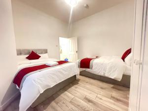 two beds in a room with white and red at Coast View Professional Let in Whitley Bay