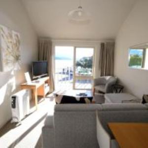 a living room with a couch and a television at La Voyageur Waterfront Apartments by AVI in Akaroa