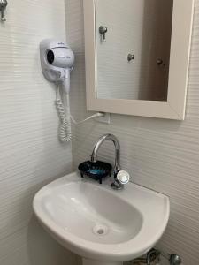 a bathroom sink with a hair dryer and a mirror at Aconchego do Vale in Blumenau