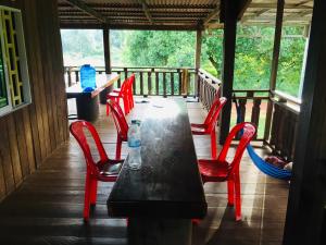 a table with red chairs and a bottle of water on a porch at Ratanakiri Farmhouse & Trekking in Banlung