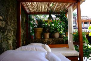 um alpendre com uma cama e plantas num quarto em Casa Turquesa - Maison D´Hôtes em Paraty