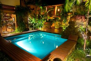 a swimming pool with a bench in a garden at Casa Turquesa - Maison D´Hôtes in Paraty