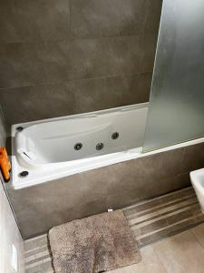 a white bath tub in a bathroom with a mirror at Casa cálida súper confortable hasta 7 personas in Esquel