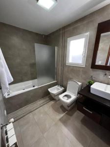 a bathroom with a toilet and a tub and a sink at Casa cálida súper confortable hasta 7 personas in Esquel