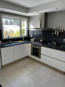 a kitchen with white cabinets and a sink and a window at Casa cálida súper confortable hasta 7 personas in Esquel