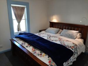 a bed with a blue blanket and a window at Alloway Bank in Bathurst +14 photos