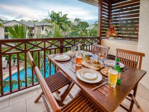 una mesa de madera con comida y bebida en el balcón en Freestyle Resort Port Douglas, en Port Douglas