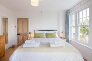 1 dormitorio blanco con 1 cama grande con almohadas verdes en Sea Dream, en St Ives