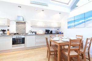 una cocina con armarios blancos y una mesa y sillas de madera. en The Sail Loft, en St Ives