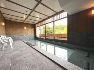 a swimming pool with a table and chairs in a building at Takasago Onsen in Asahikawa