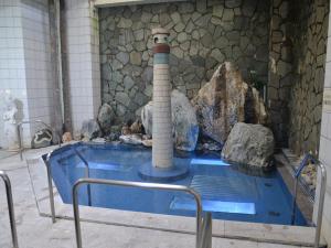a swimming pool with a lighthouse in the middle of a building at Takasago Onsen in Asahikawa