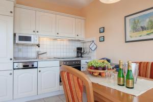 eine Küche mit weißen Schränken und einem Tisch mit einer Schale Obst in der Unterkunft Villa Linde in Göhren