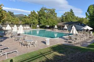 una piscina con sillas, mesas y sombrillas blancas en 703 Cottages at Silverado residence en Napa