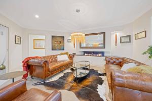 a living room with leather furniture and a table at Riverside Breeze - luxury family retreat with pool in Port Macquarie