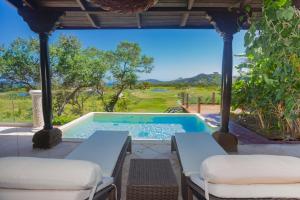 a patio with a pool and two lounge chairs at Pristine Bay 1003 home in Roatan