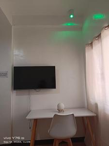 a white desk with a chair and a television on a wall at RSK Beach and Accommodation in Dapa