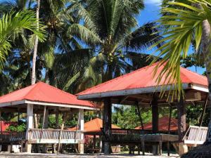 two pavilions with red roofs on a beach with palm trees at RSK Beach and Accommodation in Dapa