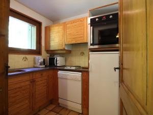 kuchnia z drewnianymi szafkami i białą lodówką w obiekcie Appartement cosy 5 pers., pied des pistes, balcon est, proche commerces, parking & services - FR-1-572-94 w mieście Arâches-la-Frasse