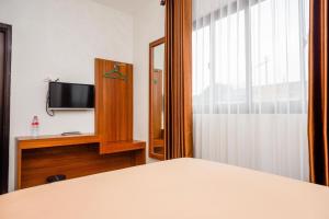 a bedroom with a bed and a tv and a window at Urbanview Hotel Nostos Wonosobo by RedDoorz in Ngasinan