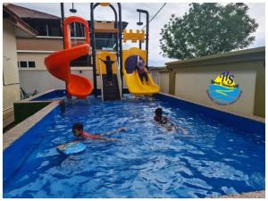 two children playing in an indoor swimming pool at Private Water Park at Cozy House HS Sweet Homestay in Cukai