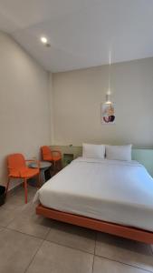 a bedroom with a large white bed with orange chairs at Raon THT Hotel in Da Lat