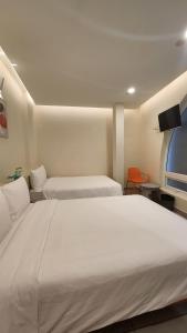 a bedroom with two beds and a flat screen tv at Raon THT Hotel in Da Lat