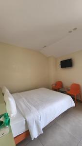 a bedroom with a white bed and two orange chairs at Raon THT Hotel in Da Lat